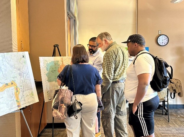 Open house attendees view a map as a project representative points out details.